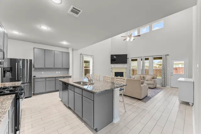 a large white kitchen with wooden floor a sink stainless steel appliances and cabinets