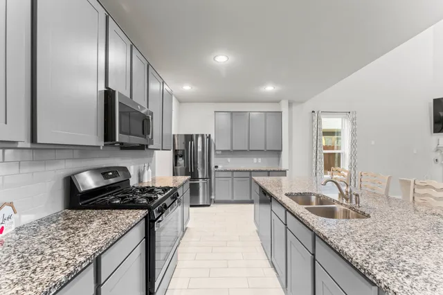 a kitchen with stainless steel appliances granite countertop a sink stove and refrigerator