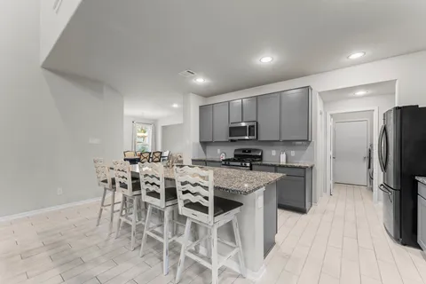 a kitchen with stainless steel appliances a microwave a stove a sink a refrigerator and chairs