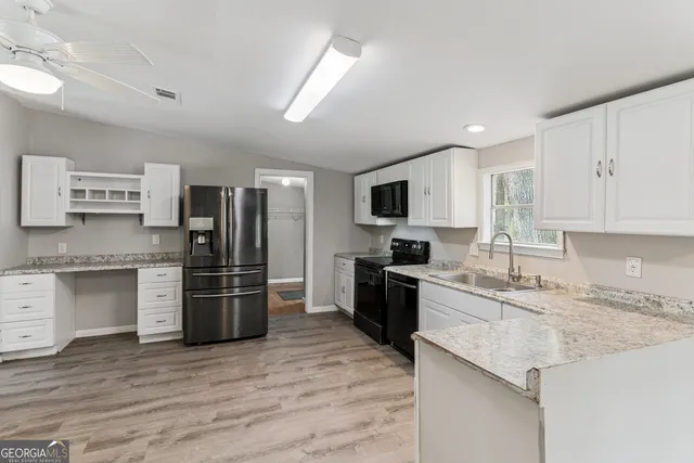 a kitchen with granite countertop a refrigerator stove top oven and sink