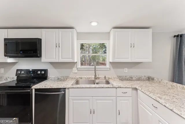 a kitchen with granite countertop white cabinets and black stainless steel appliances