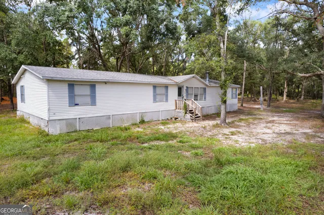 a view of a yard in front of a house with large trees