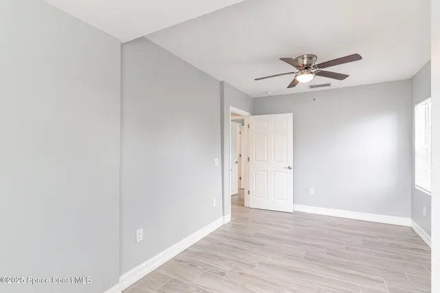 a view of a big room with wooden floor and chandelier fan