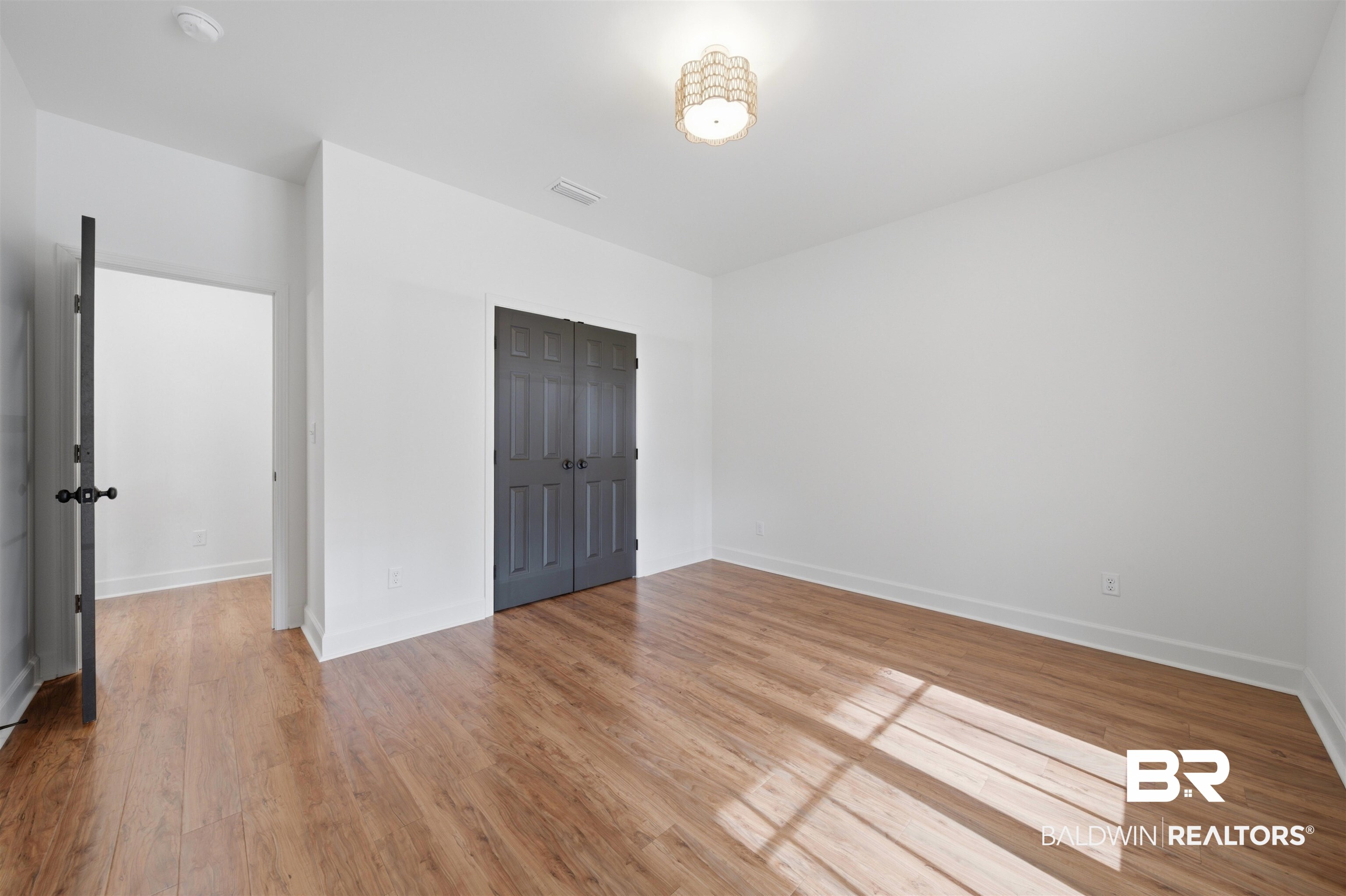 14128 Jackson Lane Foley, AL 36535 - Photo 26 of 36 Spacious room featuring wood-finish flooring, white walls, and a decorative ceiling light fixture