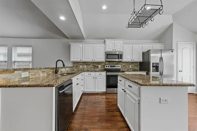 a kitchen with stainless steel appliances granite countertop a sink and dishwasher a stove top oven with wooden floor