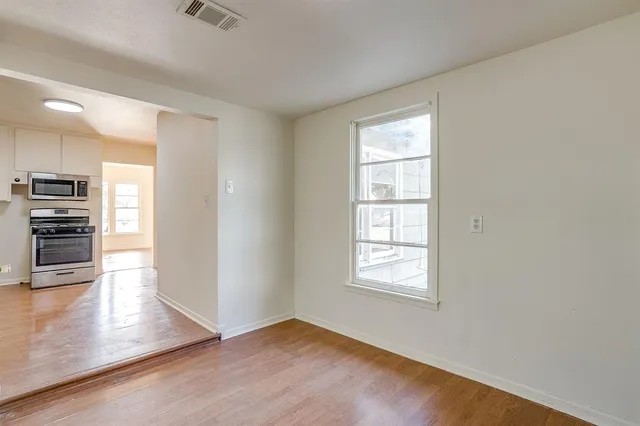 an empty room with wooden floor fan and windows