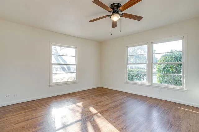 a view of empty room with wooden floor and fan