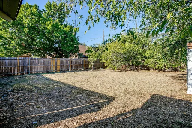 a backyard of a house with large trees and plants
