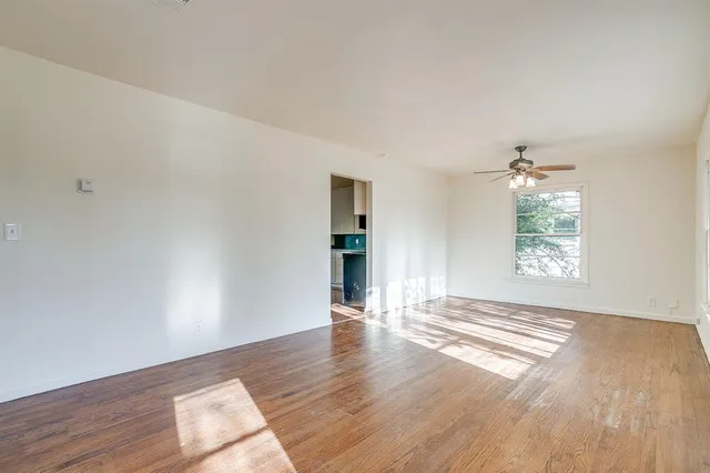 a view of an empty room with wooden floor and a window