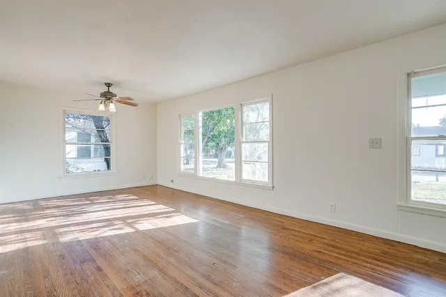 a view of an empty room with a window and wooden floor