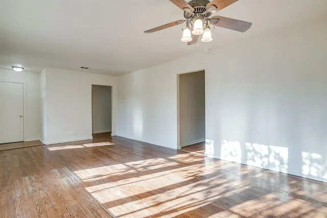 a view of an empty room with a chandelier fan
