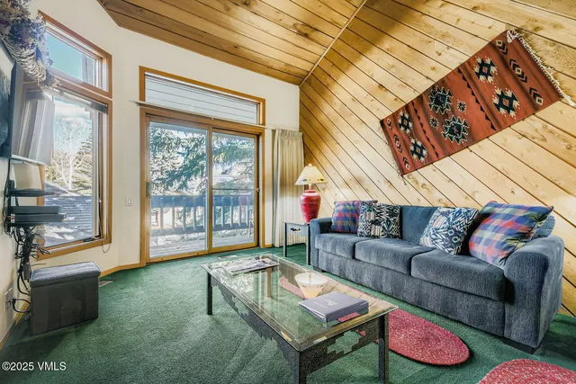 a living room with furniture a flat screen tv and a floor to ceiling window
