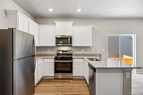 a kitchen with stainless steel appliances granite countertop a refrigerator sink and stove