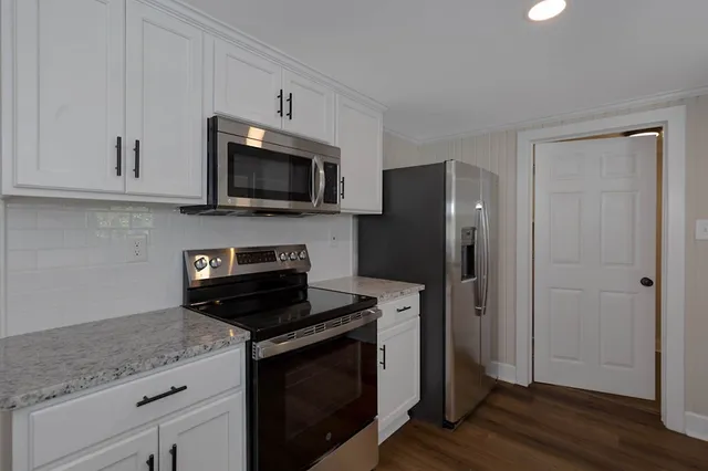 a kitchen with granite countertop a refrigerator stove and microwave