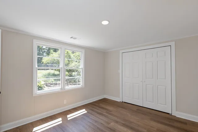 a view of an empty room with wooden floor and a window