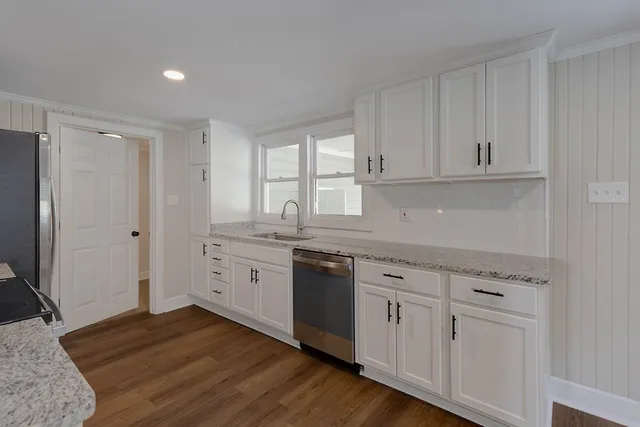 a kitchen with white cabinets and sink