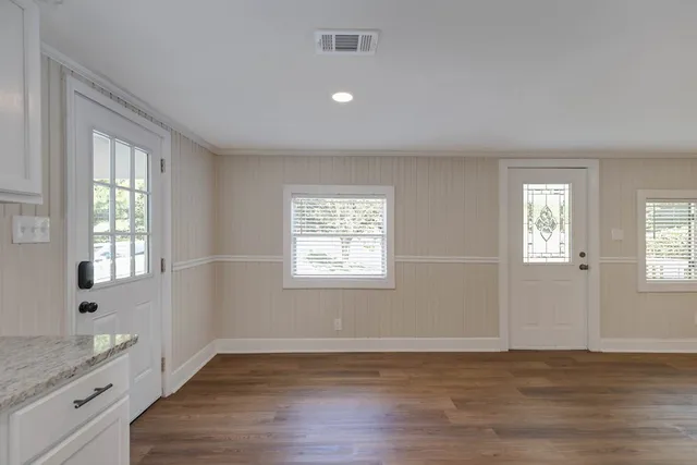 a view of an empty room with wooden floor and a window