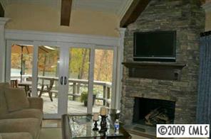 15131 Birling Road Charlotte, NC 28278 - Photo 7 of 12 a living room with a fireplace a flat screen tv and a floor to ceiling window