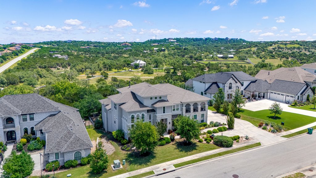 203 Lodestone Lane Austin, TX 78738 - Photo 40 of 40 Expansive residential property featuring a multi-story stucco exterior, paved driveway, landscaped front yard, and a shingle roof