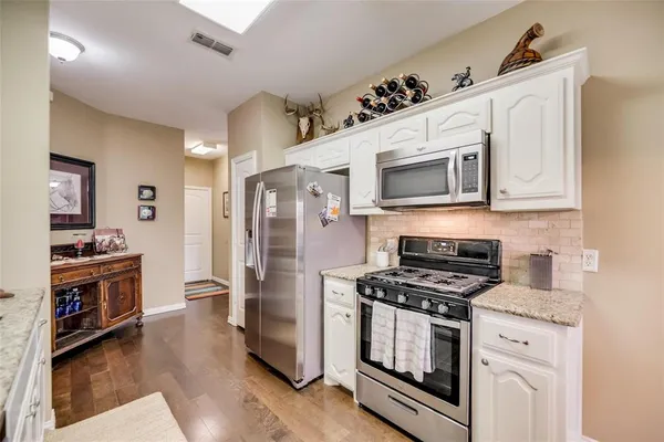 a kitchen with cabinets stainless steel appliances and wooden floor