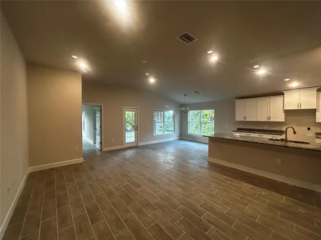 a view of an empty room with window and wooden floor