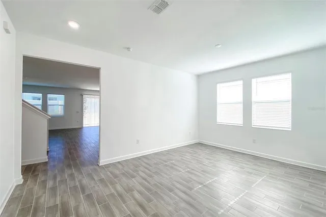 an empty room with wooden floor and windows