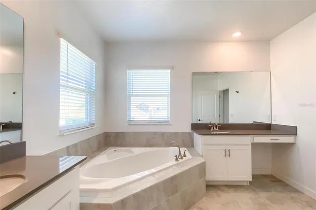 a bathroom with a granite countertop sink mirror bathtub and window