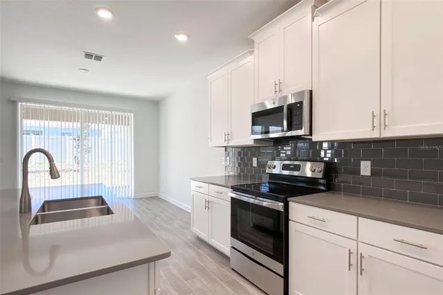 a kitchen with granite countertop white cabinets and stainless steel appliances