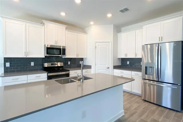 a kitchen with stainless steel appliances a refrigerator a stove a sink cabinets and a counter top space