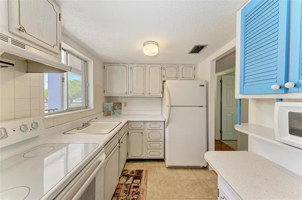 a kitchen with a sink a refrigerator and white cabinets