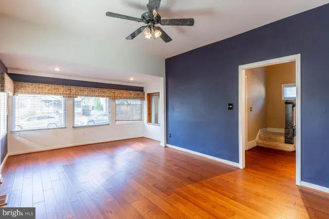 a view of an empty room with a window and wooden floor