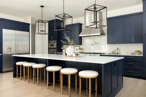 a kitchen with cabinets a sink stainless steel appliances and chairs