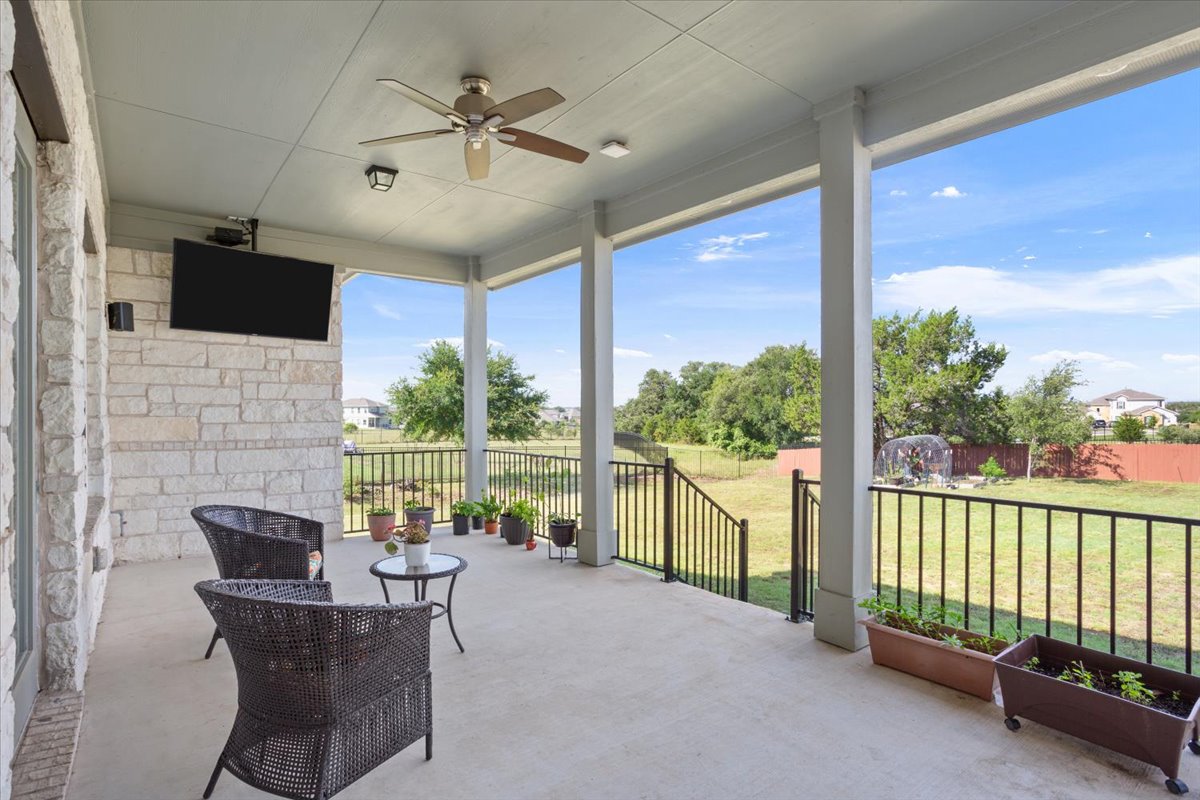 3625 Garrano Bend Leander, TX 78641 - Photo 30 of 38 An inviting covered patio with a ceiling fan provides a serene outdoor living space overlooking a lush, verdant yard.