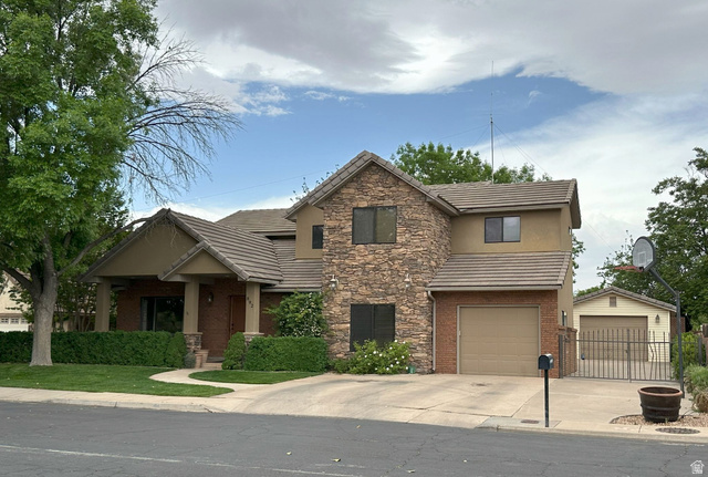 892 Cambridge Drive St. George, UT 84770 - Photo 3 of 65 Stucco and stone facade home featuring a covered front entry, attached garage with a tan door, and a detached garage with a matching tan door
