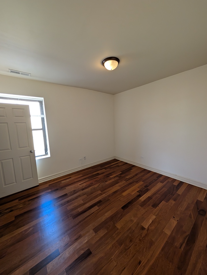 4345 North Sawyer Avenue, Unit A3 Chicago, IL 60618 - Photo 7 of 12 a view of empty room with wooden floor and fan