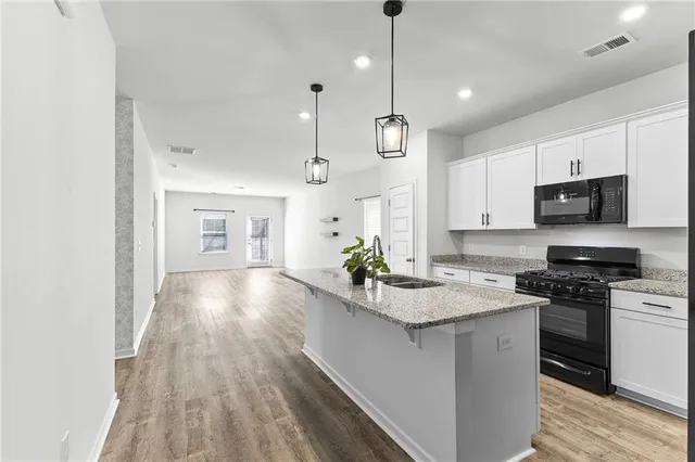 a kitchen with kitchen island granite countertop a sink a counter space appliances and cabinets