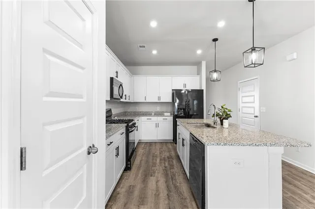 a large kitchen with granite countertop a large counter top a sink stainless steel appliances and cabinets