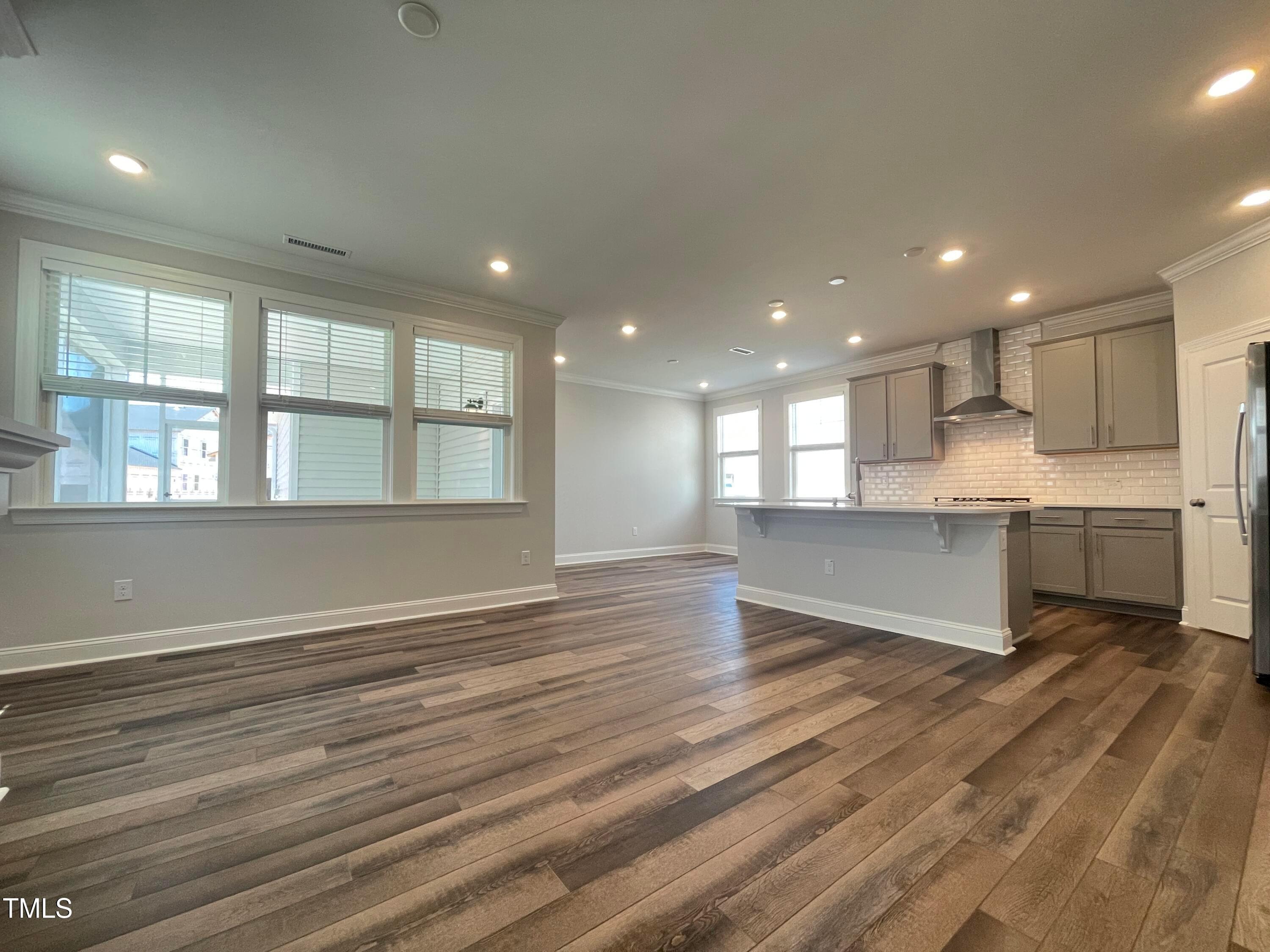 152 Baymouth Lane Raleigh, NC 27610 - Photo 3 of 25 a view of an empty room with wooden floor and kitchen