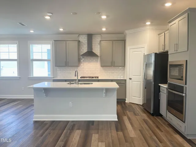 a large kitchen with stainless steel appliances granite countertop a stove a sink and a refrigerator