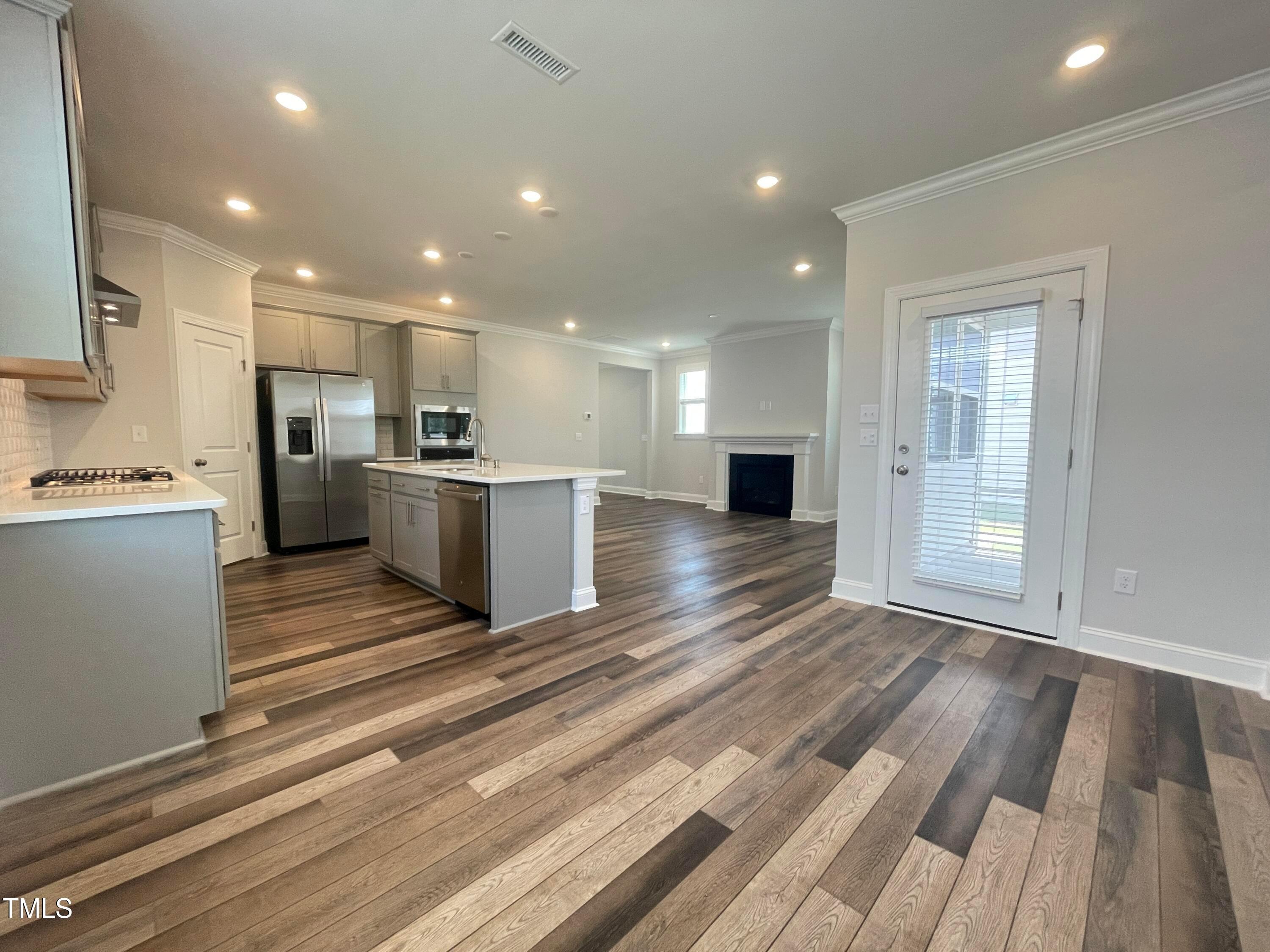 152 Baymouth Lane Raleigh, NC 27610 - Photo 10 of 25 a open kitchen with kitchen island a stove a refrigerator cabinets and a wooden floor