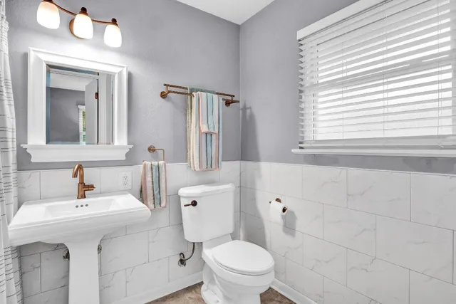 a bathroom with a sink a mirror a toilet and a window