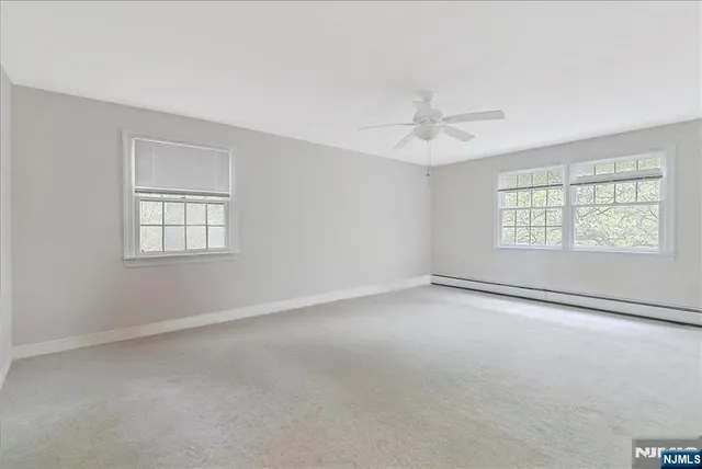 an empty room with windows and ceiling fan