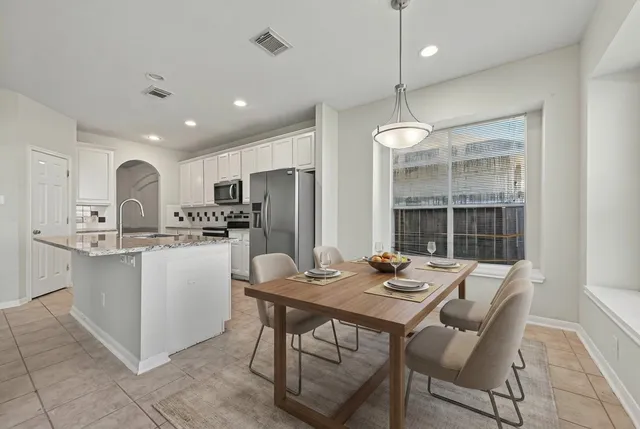 a kitchen with a dining table chairs refrigerator and cabinets