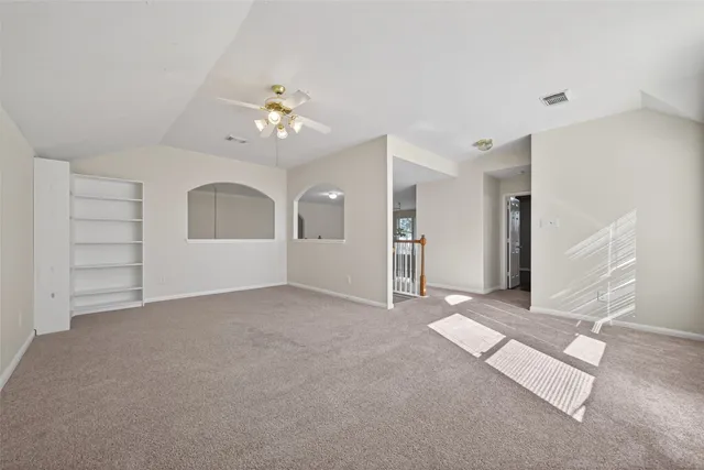 an empty room with chandelier fan and windows