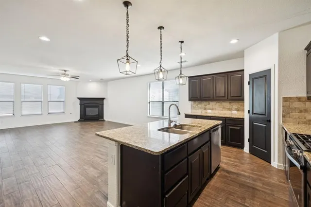 an empty room with wooden floor chandelier and windows