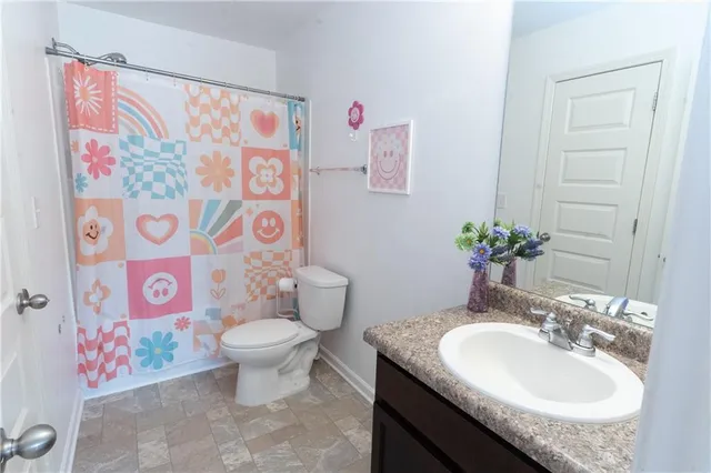 a bathroom with a granite countertop sink a toilet and a shower curtain