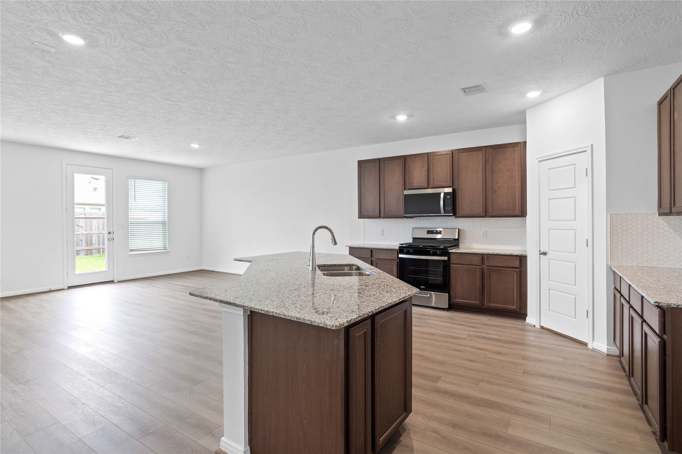 745 Imperial Loop Alvin, TX 77511 - Photo 16 of 29 a kitchen with granite countertop kitchen island wooden floors wooden cabinets and appliances