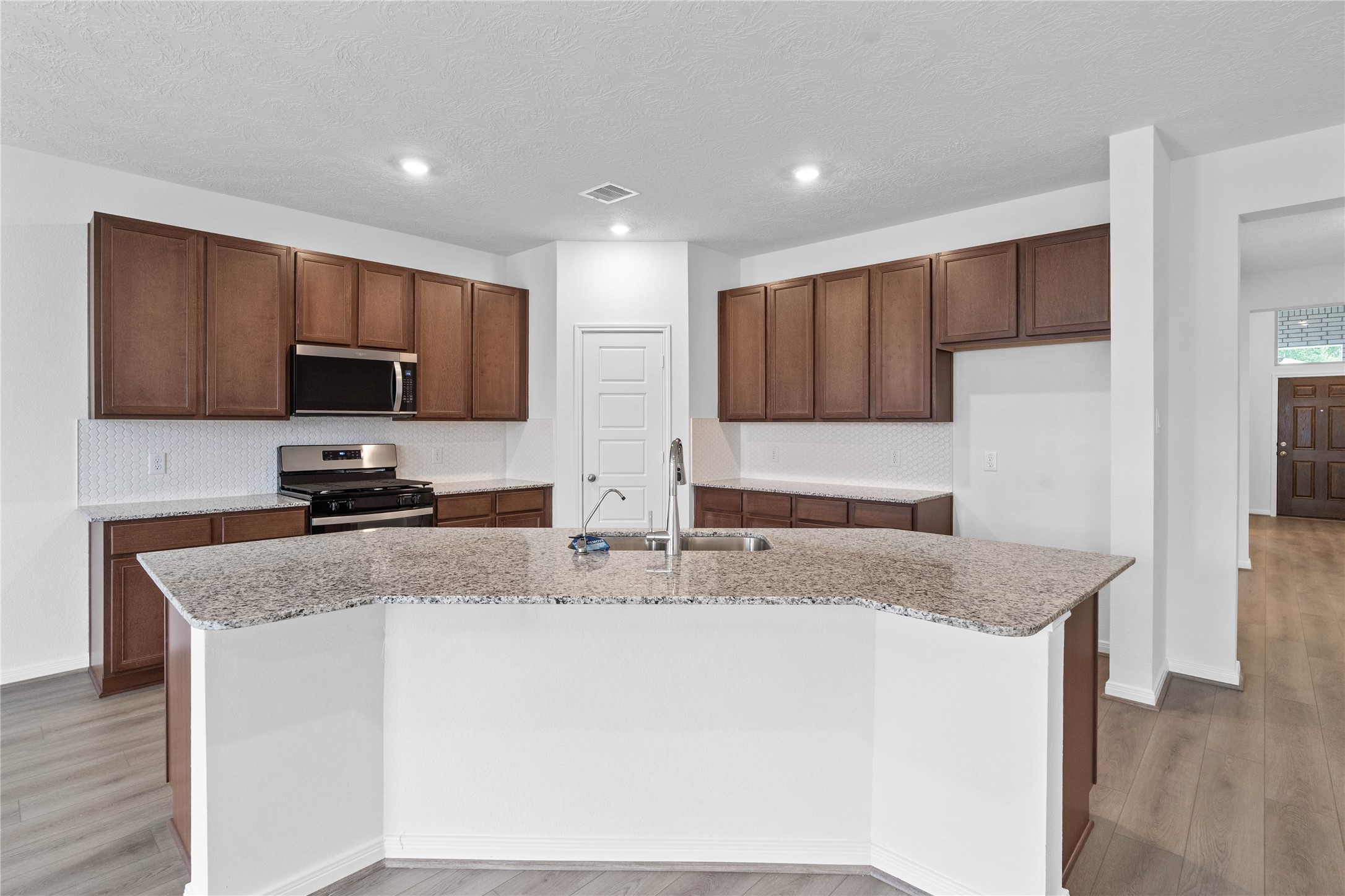 745 Imperial Loop Alvin, TX 77511 - Photo 18 of 29 a kitchen with granite countertop a sink a stove top oven a granite counter space and cabinets