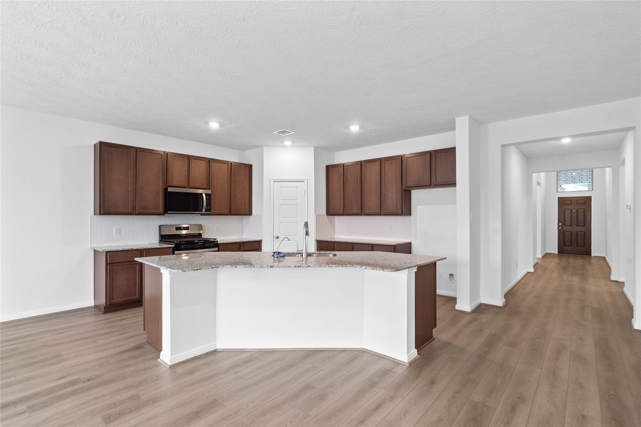 745 Imperial Loop Alvin, TX 77511 - Photo 23 of 29 a kitchen with stainless steel appliances a stove top oven a sink a refrigerator white cabinets and wooden floor