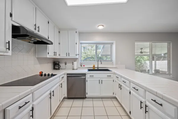 a kitchen with white cabinets appliances a sink and a window